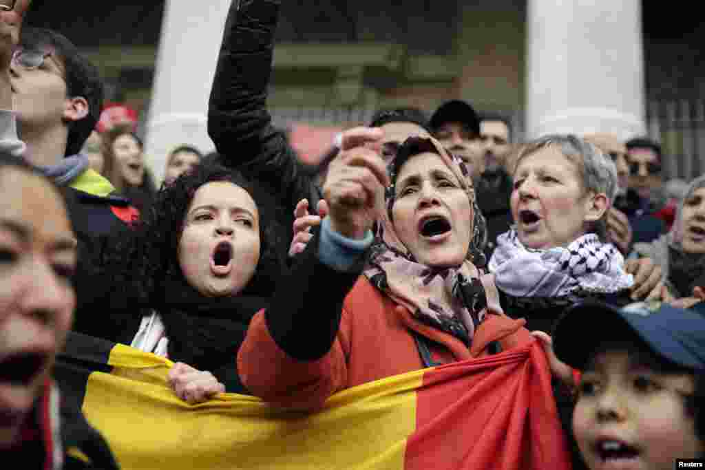 People sing as they gather around a makeshift memorial at the Place de la Bourse (Beursplein) in Brussels on March 23, 2016, a day after blasts hit the Belgian capital.