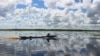 A man in a klotok boat navigates through a peat swamp near Lake Sambujur, North Hulu Sungai, South Kalimantan, Indonesia. Some peat forests have been drained for years, creating an imbalance in the water table that has left areas vulnerable to fires and flooding. (B. Hope/VOA)