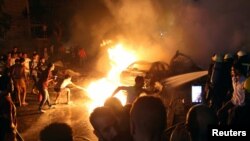 Kerumunan warga berupaya memadamkan api akibat ledakan yang dipicu oleh tabrakan kendaraan bermotor di luar kantor Lembaga Kanker Mesir, di Kairo, 4 Agustus 2019. 