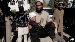 FILE - An Afghan man carries an injured boy to a hospital after two roadside bombs struck the Achin district of Jalalabad, east of Kabul, Afghanistan, Nov. 28, 2013.