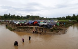 FILE - Rohingya refugees cross a stream to reach their temporary shelters at No Man's Land between the Bangladesh-Myanmar border, at Cox's Bazar, Bangladesh, Sept. 9, 2017.