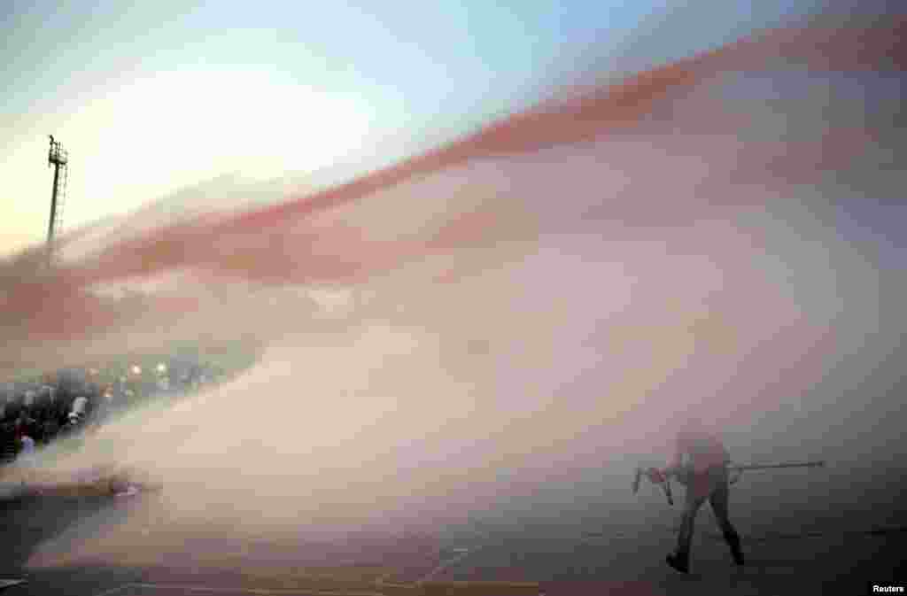 Para demonstran diserang air dari meriam yang ditembakkan polisi di pintu masuk Taman Gezi dekat Alun-Alun Taksim (15/6). (Reuters/Yannis Behrakis)