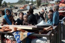 FILE - Afghan families leave their houses after fighting between the Afghan military and Taliban insurgents in Helmand province, southern Afghanistan, Oct. 13, 2020.