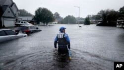 北卡罗来纳州城市搜索和救援队的一名成员2018年9月16日在费耶特维尔的倾盆大雨中，在一个被洪水淹没的街区寻找没有撤离的居民。
