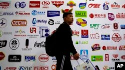 FILE - a man walks by a billboard displaying a Chinese company developed packaging machinery for local and foreign food and beverage companies at the International soybean exhibition in Shanghai. 