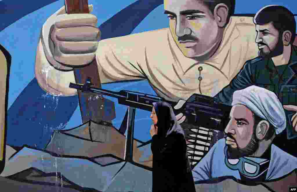 ស្រ្តី​ម្នាក់​ដើរកាត់​រូប​គំនូរ​លើជញ្ជាំង​​មួយ​ដែល​បង្ហាញ​​ពី​យុទ្ធជន​​​នៅ​តាម​ជញ្ជាំង Palestine Square ​ក្នុង​រដ្ឋ​ធានី​តេហេរ៉ង់ ​នៃ​ប្រទេស​អ៊ីរ៉ង់។ &nbsp;