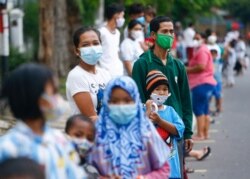 Orang-orang yang mengenakan masker pelindung antre untuk menerima makan gratis berbuka puasa selama bulan suci Ramadhan di tengah pandemi COVID-19 di Jakarta, 15 April 2021. (Foto: REUTERS/Ajeng Dinar Ulfiana)