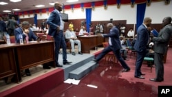 A lawmaker steps over a large puddle of water on the Parliament floor, created by rain water leaking through the roof, as lawmakers meet to debate whether or not to start impeachment proceedings for Haitian President Jovenel Moise in Port-au-Prince, Haiti