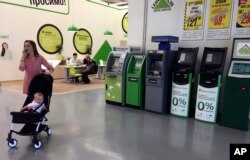 Seorang wanita melintasi mesin-mesin ATM yang tidak berfungsi akibat serangan siber di ibukota Ukraina, Kiev