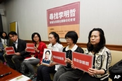 FILE - In this photo taken March 24, 2017, Lee Ching-yu, third from right holds up a photo of her missing husband and Taiwanese pro-democracy activist Lee Ming-che during a press conference.