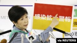 Tokyo Governor Yuriko Koike shows a banner reading 'Infection spread alert' during a news conference on the latest situation of the coronavirus disease (COVID-19) outbreak, in Tokyo, Japan, July 15, 2020, in this photo taken by Kyodo.