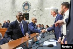 امریکی وزیر دفاع لائڈ آسٹن اور چئیرمین جوائنٹ چیفس آف اسٹاف جنرل چارلس براؤن سینیٹ میں مسلح افواج کی کمیٹی کی سماعت سے قبل سینیٹرز سے ہاتھ ملا رہے ہیں، فوٹو رائٹرز 9 اپریل 2024