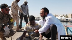 FILE - Migrants receive medical treatment after being rescued at sea by the Libyan coast guard, in Tripoli, Libya, April 11, 2016. 