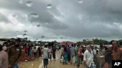 Rohingya refugees walk under rain clouds on June 26, 2018, in Jamtoli refugee camp in Bangladesh.