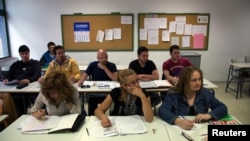FILE - Victor Antu–a of Spain (top R) and Felipe Barbosa of Colombia (top 2nd R) attend an English class at an Adults Education Centre in Madrid.