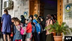 Children walk out of a building during the handover of orphaned children, whose parents were suspected of belonging to the Islamic State group, to a Russian delegation by Syrian Kurdish officials, in Syria's northeastern city of Qamishli, April 18, 2021.
