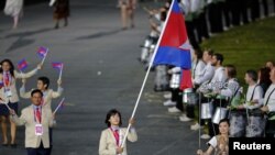 Cambodia's flagbearer Davin Sorn holds the national flag as she leads the contingent in the athletes parade during the opening ceremony of the London 2012 Olympic Games at the Olympic Stadium July 27, 2012. REUTERS/Mike Blake (BRITAIN - Tags: SPORT OLYMPICS) 