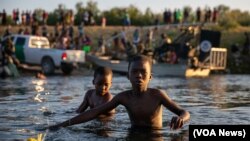 Two Haitians brothers cross the Rio Bravo natural border between Del Rio and Ciudad Acuña, Sept. 20, 2021. (Stephania Corpi/VOA)