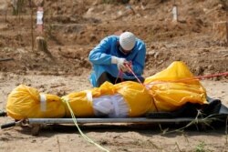 A man wearing a protective gear mourns next to the body of his father who died from the coronavirus disease (COVID-19), at a graveyard in New Delhi, India, May 2, 2020.