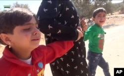 This frame grab from video provided by Muaz al-Shami, Syrian Revolution Network, an opposition activist media organization, that is consistent with independent AP reporting, shows children pulled by an adult after airstrikes killed nearly 30 people, mostl