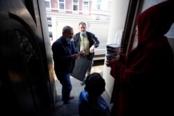 Relawan Turki Goecen Muelayim, 55, (kiri) dan Ural Hasan, 55, dari layanan pengiriman makanan buka puasa, membagikan makanan kepada seorang perempuan Muslim yang membutuhkan dan anaknya selama Ramadan di tengah pandemi COVID-19 di Wupperta, Jerman. (Foto: dok).