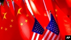 FILE - American flags are displayed together with Chinese flags on top of a trishaw in Beijing, Sept. 16, 2018.