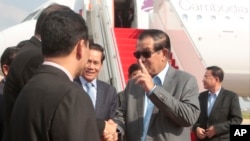 Cambodian Prime Minister Hun Sen, second from right, talks with his government offers as he arrives from Laos, at the airport in Phnom Penh, Cambodia, Saturday, Aug. 12, 2017. Hun Sen, who threatened Friday to use force over a border crisis with neighboring Laos, has announced less than 24 hours later that he has peacefully resolved it. (AP Photo/Heng Sinith)
