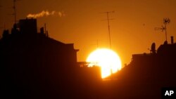 FILE - The sun sets over buildings in Milan, Italy, Dec. 14, 2018.
