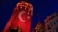 People take photos at the iconic Galata Tower, illuminated in Turkish flag colors, in Istanbul, July 30, 2016. Some signals from President Recep Tayyip Erdogan's administration show no letup in reprisals following an abortive coup attempt two weeks ago.