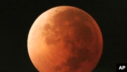 FILE - In this Aug. 28, 2007, file photo, the moon takes on different orange tones during a lunar eclipse seen from Mexico City. On Jan. 31, 2018, a super moon, blue moon and a lunar eclipse will coincide for first time since 1982 and will not occur again until 2037. (AP Photo/Marco Ugarte, File)