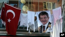 With her clothes hanging to dry on a balcony, a woman listens to Turkish Prime Minister Ahmet Davutoglu during a rally of his Justice and Development Party, or AKP, in Ankara, Oct. 31, 2015.