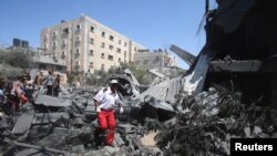 Seorang petugas medis Palestina berjalan di tengah reruntuhan rumah yang hancur akibat serangan Israel di Rafah, Jalur Gaza (14/7). (Reuters/Ibraheem Abu Mustafa)