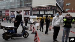 Residents wearing masks to protect against the spread of the coronavirus line up to enter a supermarket in Wuhan in central China's Hubei province on April 3, 2020. 