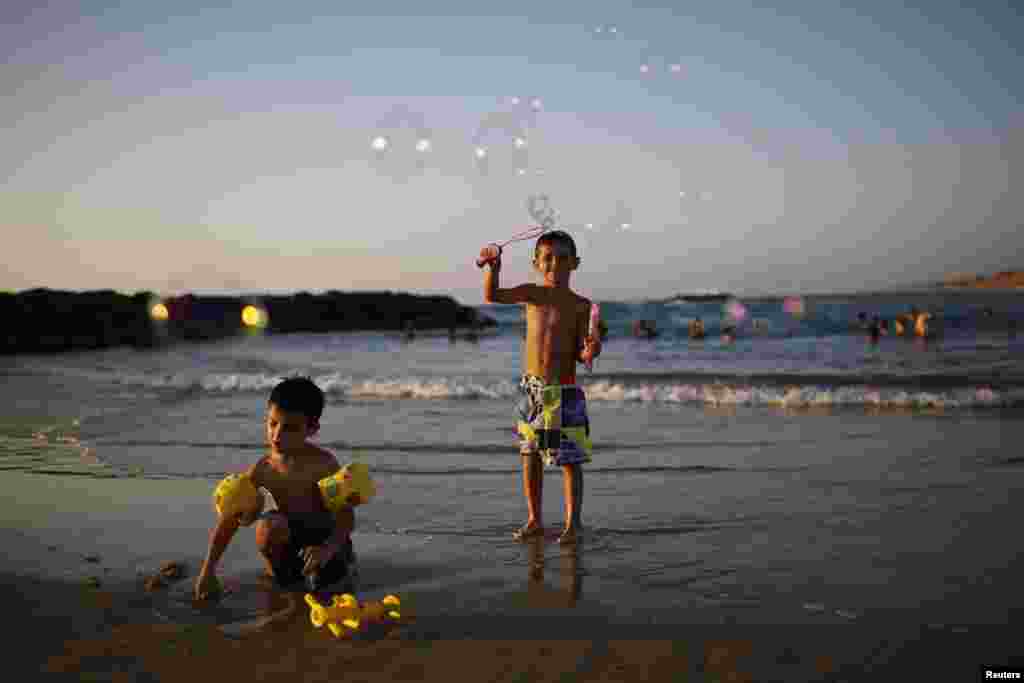 A child blows soap bubbles on the shore of the Mediterranean sea at the southern Israeli city of Ashkelon August 11, 2014.