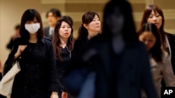 FILE - Female office workers head to their workplace during morning rush hour in Tokyo. Without a substantial increase in the birthrate or loosening of staunch Japanese resistance to immigration, the population is forecast to fall to about 108 million by 2050 and to 87 million by 2060.