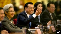 Chinese Premier Li Keqiang, center, smiles as he answers a reporter's question during a press conference at the end of the National People's Congress in Beijing's Great Hall of the People, March 15, 2015. 