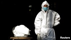 បុគ្គលិក​សុខាភិបាល​ម្នាក់​ពាក់​ឧបករណ៍​ការពារ​ខ្លួន PPE ឈរ​ជិត​សាកសព​របស់​មនុស្ស​ម្នាក់ ដែល​ស្លាប់​ដោយ​សារ​ជំងឺ​កូវីដ១៩ នៅ​ទីក្រុង​ញូវដេលី ប្រទេស​ឥណ្ឌា ថ្ងៃទី ២៨ ខែកញ្ញា ឆ្នាំ២០២០។ 