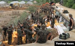 19일 폭염 주의보가 내려진 가운데 천안시 수신면 방산리에서 32사단 장병들이 무너진 도로를 흙으로 채우고 있다. (천안시 제공)