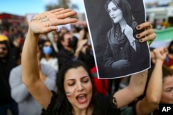 A woman holds up a drawing of Iranian Mahsa Amini as she shouts slogans during a protest against her death, in Istanbul, Turkey, Sunday, Oct. 2, 2022.