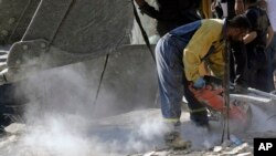 An emergency worker cuts concrete blocks as he searches for survivors at the scene of an Israeli airstrike in the town of Maisara, north of Beirut, Sept. 25, 2024.