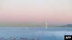 FILE - Smog covers the Siberian industrial city of Krasnoyarsk, Russia, Jan. 4, 2018. The Siberian town of Verkhoyansk recently reported an unprecedented temperature of 38 degrees Celsius.