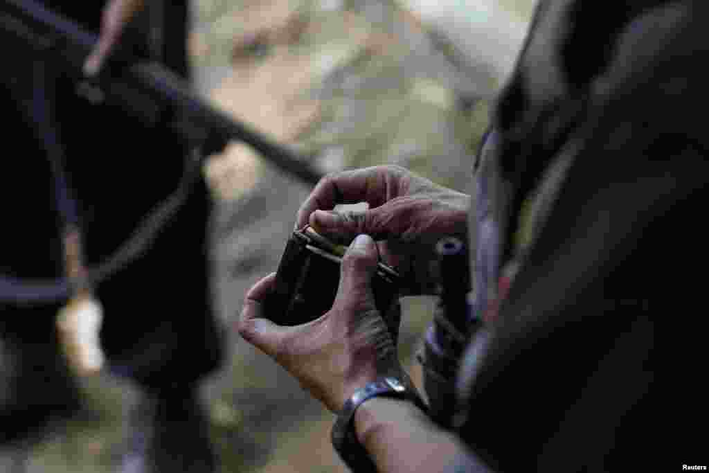 A police officer loads bullets into a magazine as he stands guard in front of a courthouse as student protesters arrive in a police van, in Letpadan, March 11, 2015.