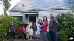 Thuy Do, second from right, poses for a photo with her husband, Jesse Robbins, right, and their son, Fredrick, Monday, Sept. 20, 2021. (AP Photo/Ted S. Warren)