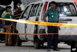 FILE - Members of Bangladeshi police and detective branch stand by the site a man was gunned down in Dhaka, Bangladesh, Sept. 29, 2015. Islamic militants claimed responsibility.