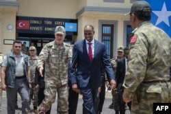 Turkish army Chief of General Staff Hulusi Akar, left, escorts Somalia Prime Minister Hassan Ali Kheire during an inauguration ceremony of the Turkish military base in Mogadishu on Sept. 30, 2017.