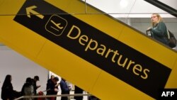 FILE - A passenger heads towards the Depatures Hall as others queue with their luggage in the South Terminal building at London Gatwick Airport, south of London, Britain, Dec. 21, 2018.