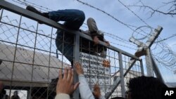 یک مهاجر افغان در حال عبور از موانع مرزی میان یونان و مقدونیه