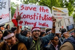 FILE - A man holds a placard as he shouts slogans to protest India's new citizenship law, during a demonstration in New Delhi, Jan. 20, 2020.