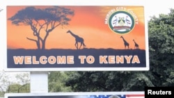 A woman sweeps next to a billboard displaying pictures of Kenya's President Uhuru Kenyatta (L) and visiting U.S. President Barack Obama, who is expected to arrive for a three-day state visit, in Kenya's capital Nairobi, July 24, 2015.