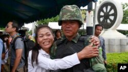 A pro-government demonstrator embraces a Thai soldier during a cleanup operation at a pro-government demonstration site on the outskirts of Bangkok, Thailand, May 23, 2014. 